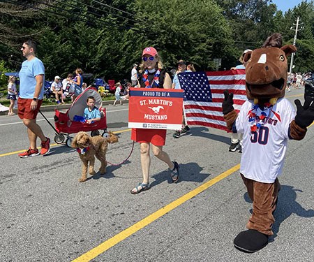 St. Martin's in-the-Field Episcopal Church parade with mascot, flags, and community members on a sunny day.